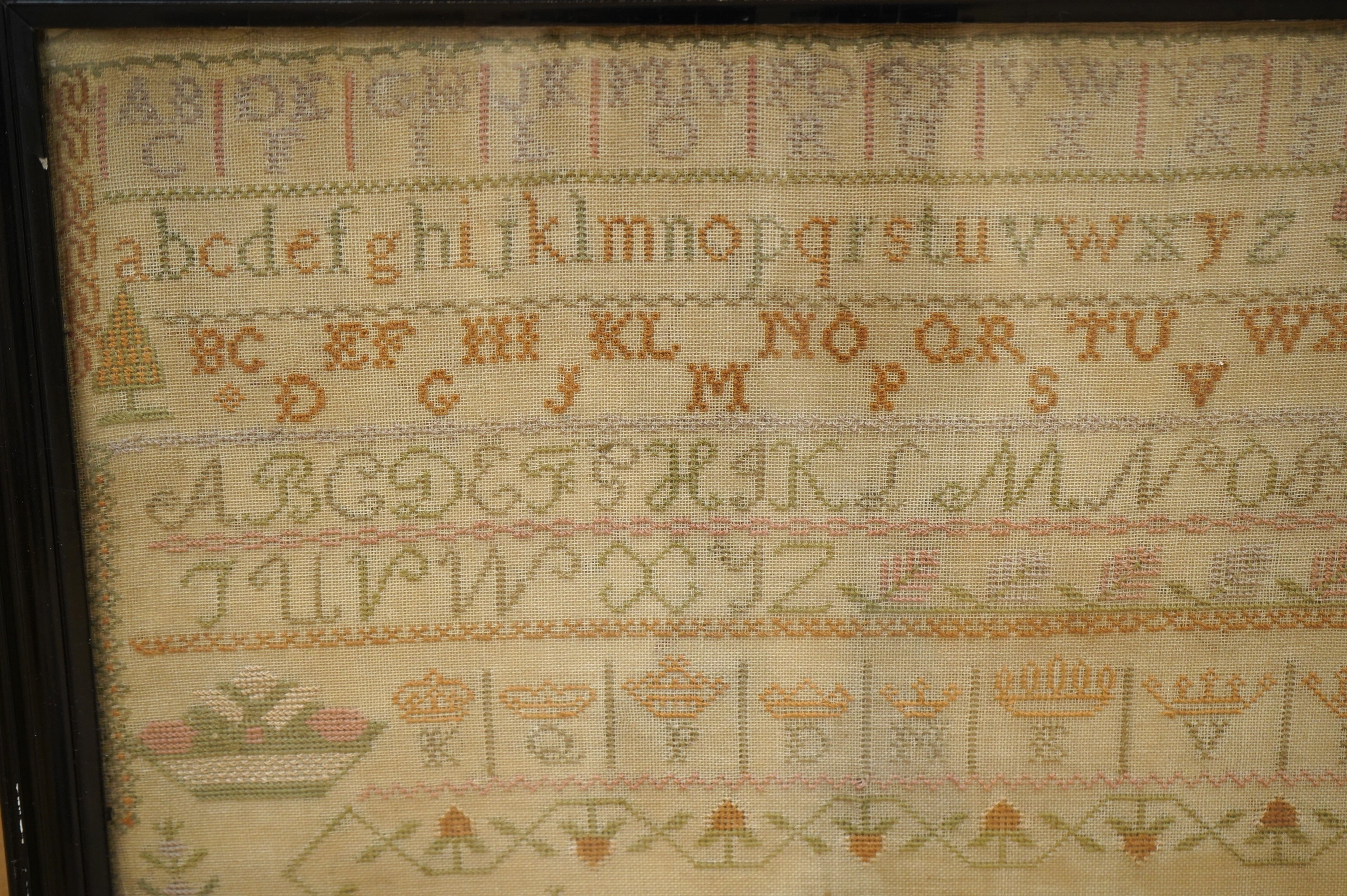 Two samplers; one late 18th century, the other early 20th century, the 18th century sampler by Elizabeth Chamberlain dated 1777, worked with an alphabet and framed verse bordered with vineous flowers, the later sampler b